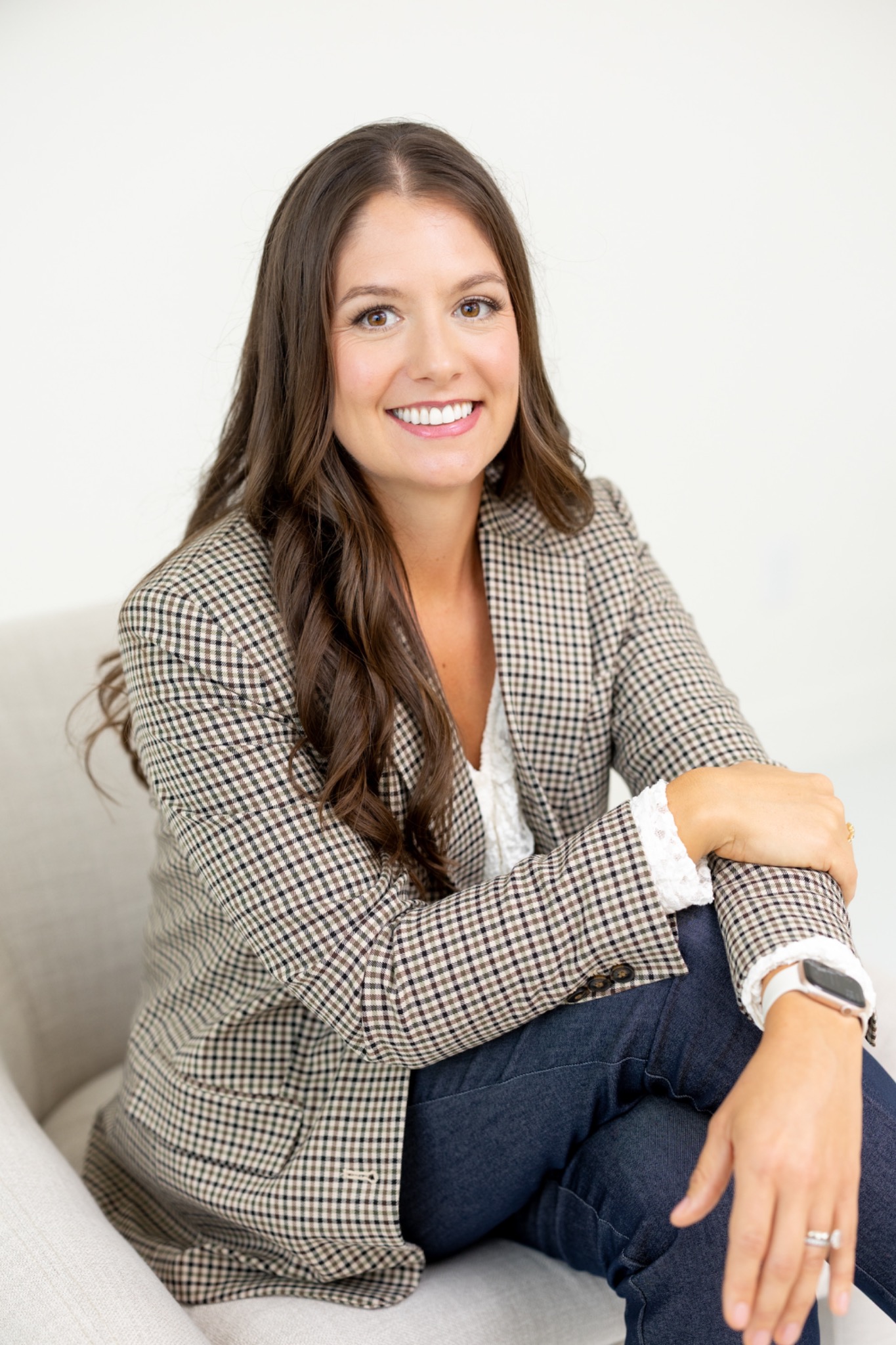 Jena Balke seated in a cream chair, wearing a checked blazer